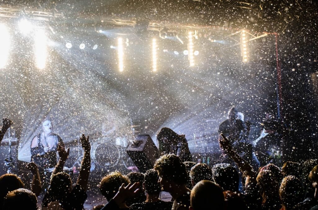 A dynamic live music concert scene with performers and an enthusiastic audience under bright stage lights.