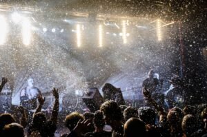A dynamic live music concert scene with performers and an enthusiastic audience under bright stage lights.